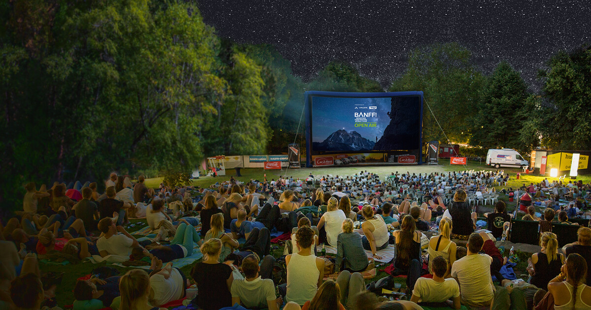 Banff Tour 2026 Open Air &ndash; Open-Air-Publikum auf einer Wiese vor einer aufblasbaren Leinwand der Banff Tour bei einer Vorf&uuml;hrung unter freiem Sternenhimmel.