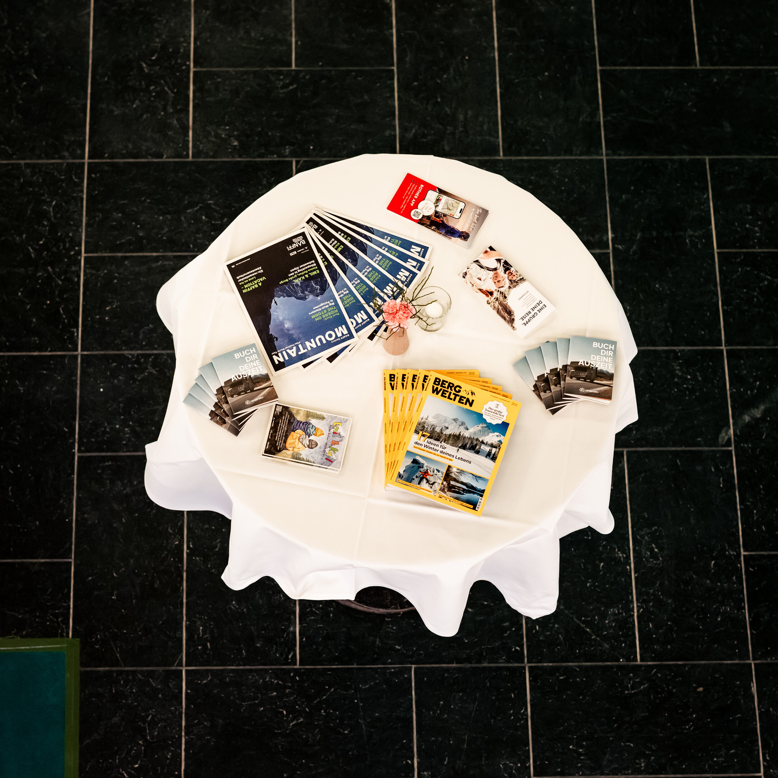 Standing table with programme booklets and magazines laid out at a Banff Tour event, shot from above.