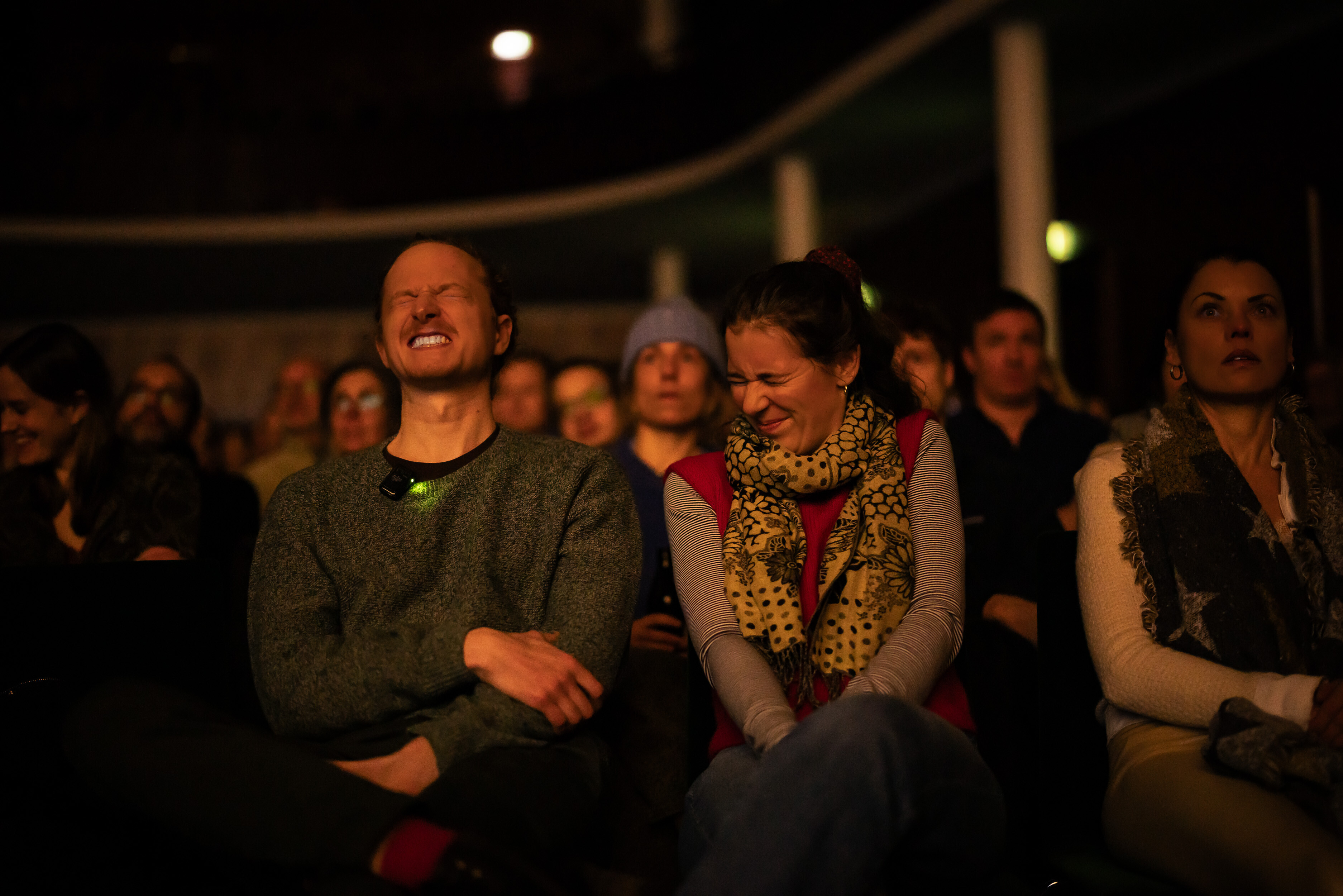 Two audience members laughing among the crowd at a Banff Tour event in the darkened hall.