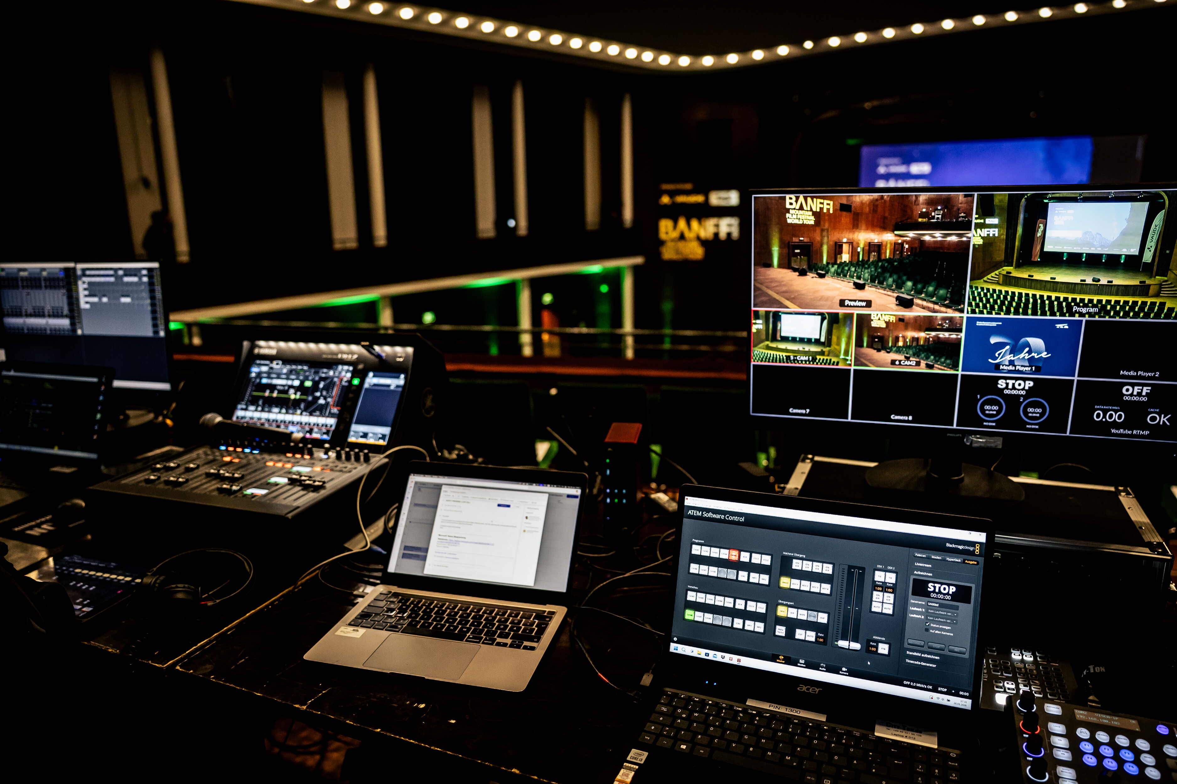 Control desk with mixing console, laptops and a monitor of the livestream production at a Banff Tour event.